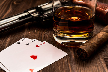 Wall Mural - Glass of whiskey and playing cards with revolver and cuban cigar on the wooden table