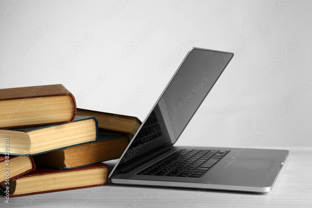 Stack of books with laptop on gray background