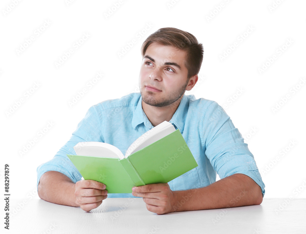 Young man reading book at table on white background