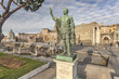Bronze statue of the roman emperor Nerva with ruins of roman forum