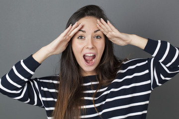 surprise and success concept - amazed 20s woman putting both hands on her face shouting for surprise and happiness