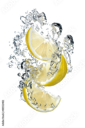 Fototapeta na wymiar Three slices of lemon falling into water