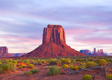 Monument Valley In Utah And Arizona, Sunrise Or Sunset With Dramatic Clouds, Desert Landscape Of Navajo Nation Park Is A Famous Travel Destination For It's Red Rock Formations