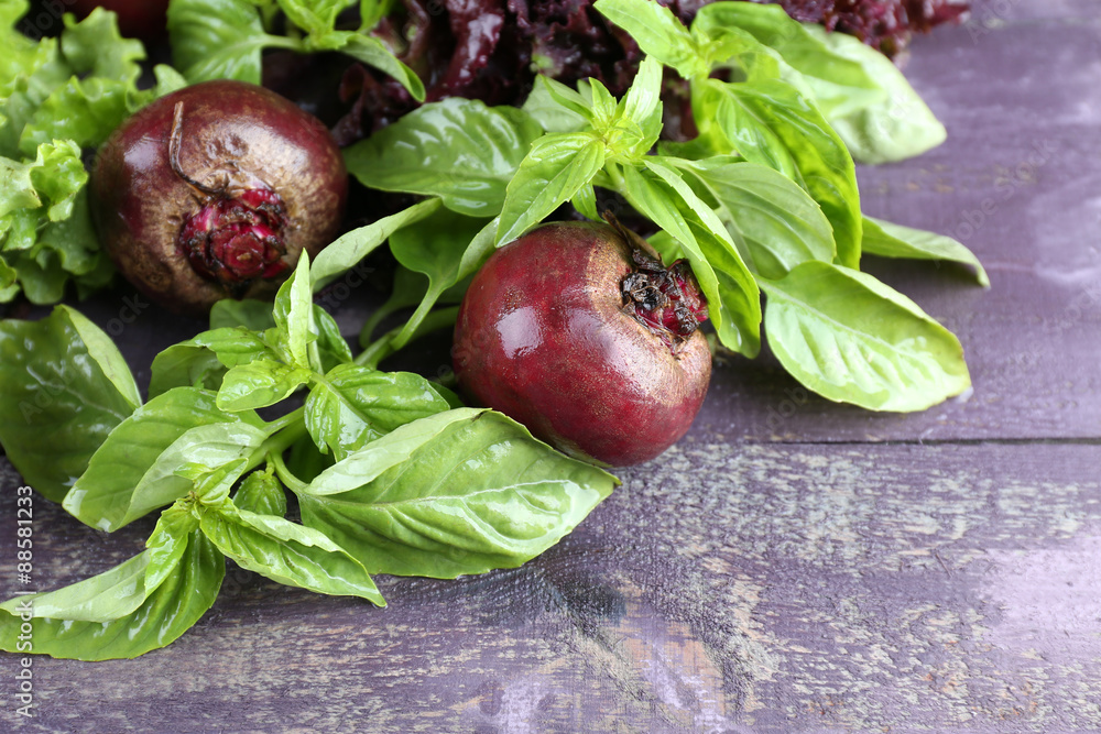 Red beets with greens on wooden table close up