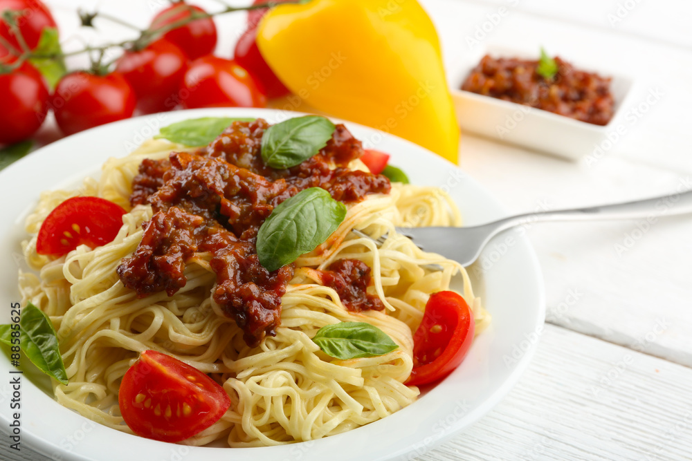 Spaghetti Bolognese on white plate, on color wooden background