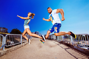 Funny young couple is jumping catching each other outdoors