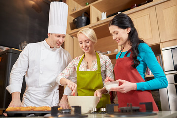 Wall Mural - happy women and chef cook baking in kitchen