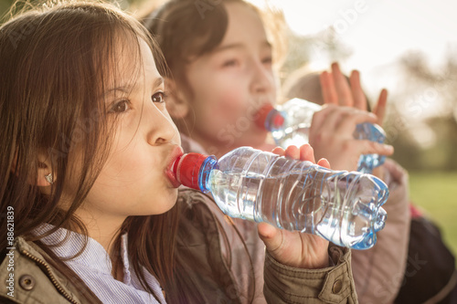 Fotografía Photo of two girls drinking water from PET bottle