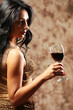 Pretty young woman with wineglass on brown background