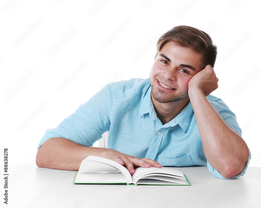 Young man reading book at table on white background
