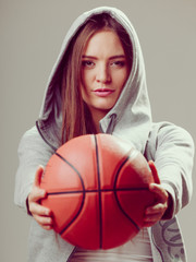 Sporty teen girl in hood holding basketball.