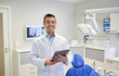 © Syda Productions - happy male dentist with tablet pc at dental clinic