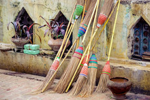 Detail Of Colorful Rustic Brooms Against Weathered Wall