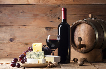 Wall Mural - Red wine with various types of cheese on wooden background