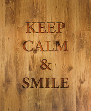 Text "Keep Calm & Smile" Engraved In Wooden Background