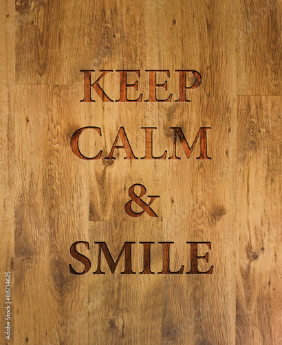 Fotomural Text Keep Calm & Smile engraved in wooden background