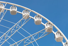 Part Of White Ferris Wheel Against Blue Sky Background