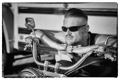 Photo  Tough guy with sun glasses lolling on his chopper motorcycle.