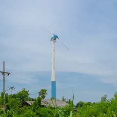 White wind turbine generating electricity on blue sky