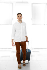 Wall Mural - Man holding suitcase on light background