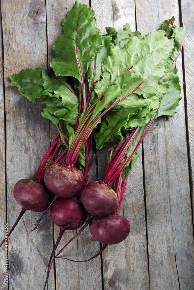 Young beets with leaves on wooden table close up