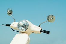 Detail Of Classic Off-white Scooter With Headlight, Handlebar And Mirrors Against Blue Sky