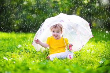 Wall Mural - Little girl with colorful umbrella playing in the rain. Kids play outdoors by rainy weather in fall. Autumn outdoor fun for children. Toddler kid outside in the garden. Baby enjoying summer shower.