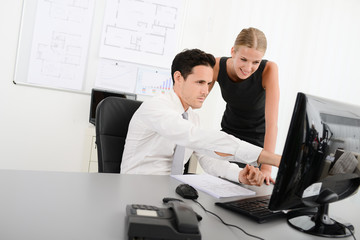 Wall Mural - two young business people in office meeting and looking at data in computer