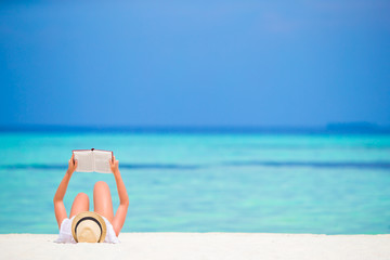 Happy girl reading during tropical white beach