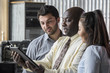 © Burlingham - Caucasian male, African American male, and Asian female looking at a tablet in the office