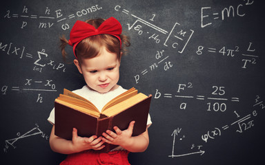 wunderkind little girl schoolgirl with a book from the blackboar