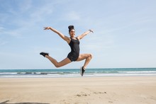 Fit Woman Leaping On The Sand