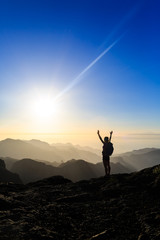 Wall Mural - woman hiking success silhouette in mountains sunset