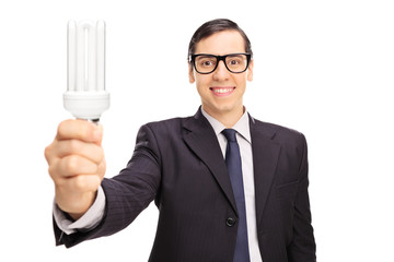 Poster - Young businessman holding an energy saving light bulb