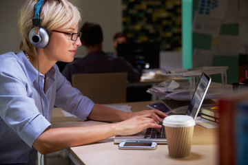 Female Office Worker With Coffee At Desk Working Late