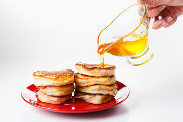 Wall Mural - Chef pours sweet syrup on pancakes. White background