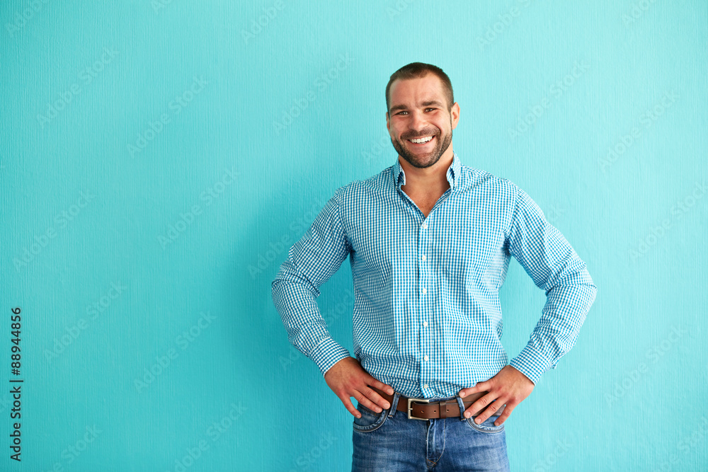 Happy man in front of turquoise wall - obrazy, fototapety, plakaty 
