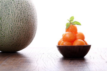 Organic cantaloupe melon in wooden bowl isolated on white backgr