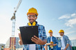 © Syda Productions - builder in hardhat with clipboard at construction