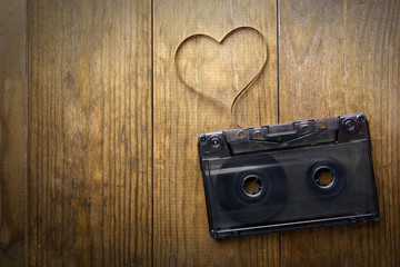 Wall Mural - Audio cassette with magnetic tape in shape of heart on wooden background