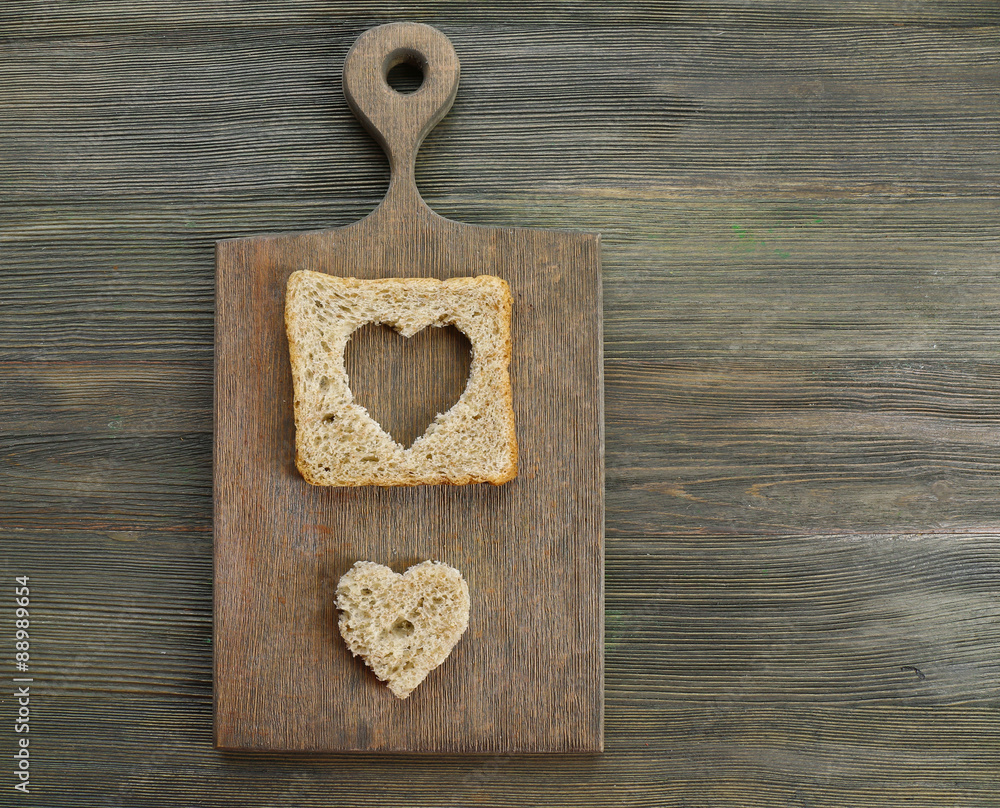 Bread slice with cut in shape of heart on wooden background