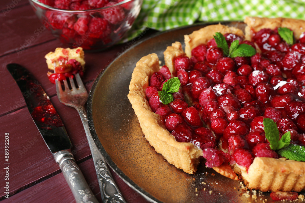Tart with raspberries on tray, on wooden background