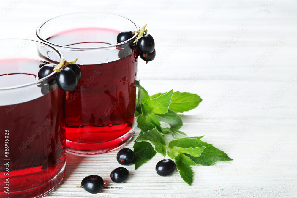 Glasses of fresh blackcurrant juice wooden table background