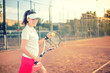 © aboutmomentsimages - Attractive brunette playing tennis and smiling at camera. Healthy modern lifestyle with sportswoman and accesssories