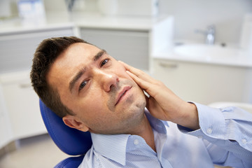 Wall Mural - man having toothache and sitting on dental chair