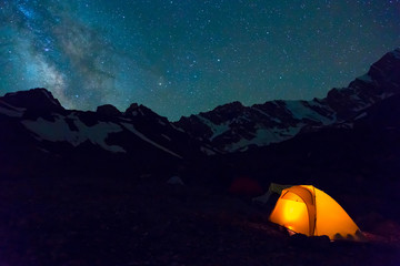 night mountain landscape with illuminated tent silhouettes of snowy mountain peaks and edges night s