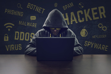 hooded cyber criminal stealing secrets with laptop