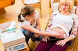 Hebamme untersucht Bauch einer schwangeren Frau mit CTG in Praxis