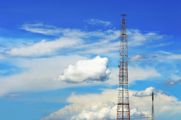 Telecommunications tower over floating cloudy blue sky background.