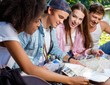 © Nejron Photo - Multiracial friends tourists in a park with map